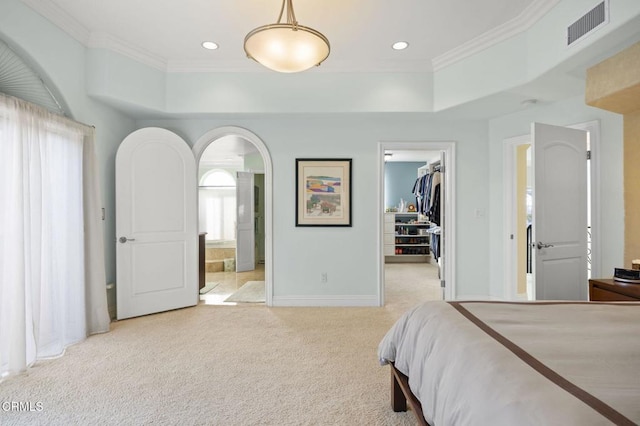 carpeted bedroom with connected bathroom, a walk in closet, ornamental molding, and a closet