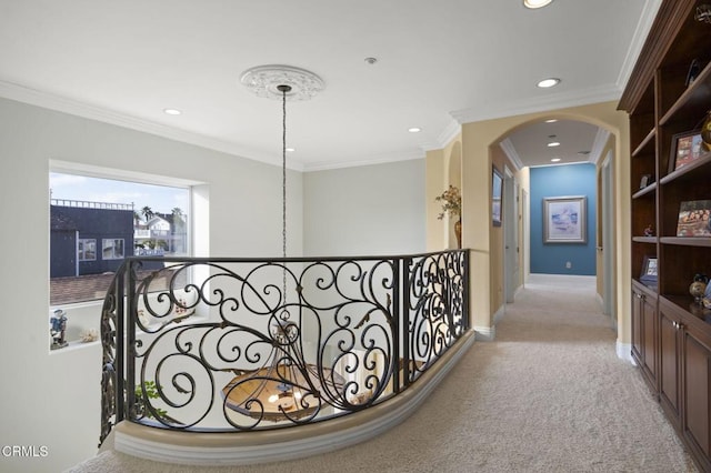 corridor with ornamental molding and light colored carpet