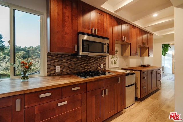 kitchen featuring tasteful backsplash, appliances with stainless steel finishes, wood counters, and light hardwood / wood-style flooring