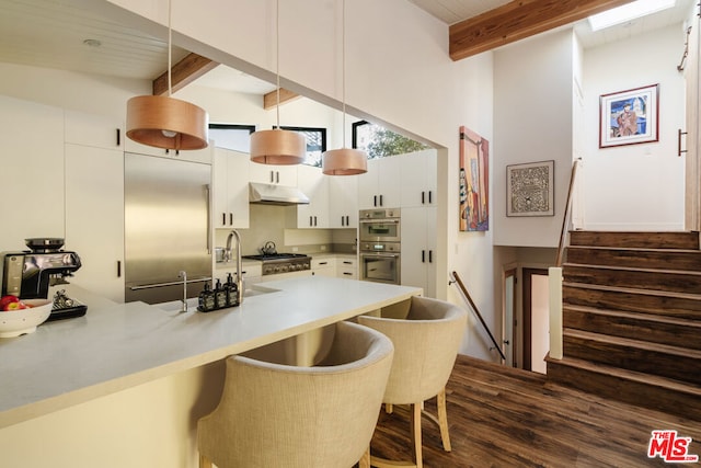 kitchen with beamed ceiling, a breakfast bar area, hanging light fixtures, and white cabinets