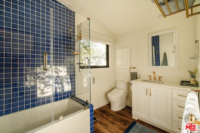 bathroom with wood-type flooring, lofted ceiling, vanity, and toilet