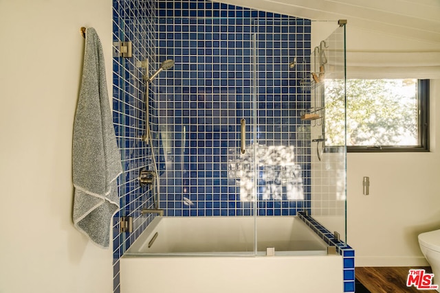 bathroom with hardwood / wood-style floors, bath / shower combo with glass door, and toilet