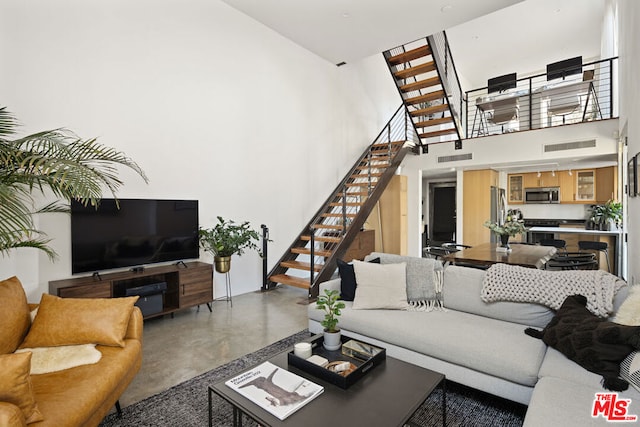 living room featuring concrete floors and a high ceiling