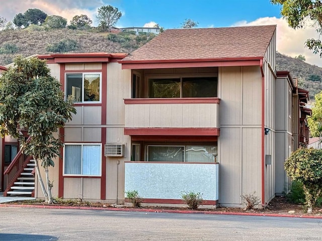 view of front facade with a balcony and an AC wall unit