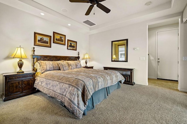 bedroom featuring light carpet, ceiling fan, and a tray ceiling