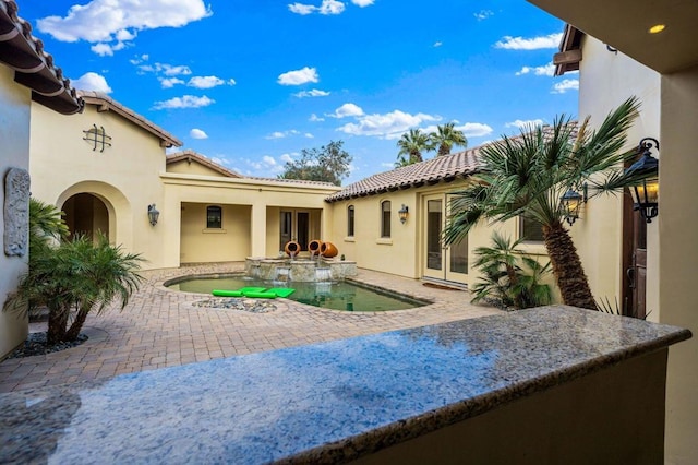 back of house with a swimming pool with hot tub and a patio