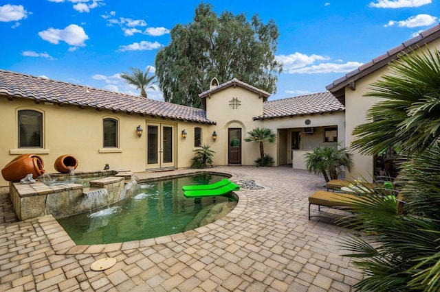 rear view of house with french doors, pool water feature, and a patio area