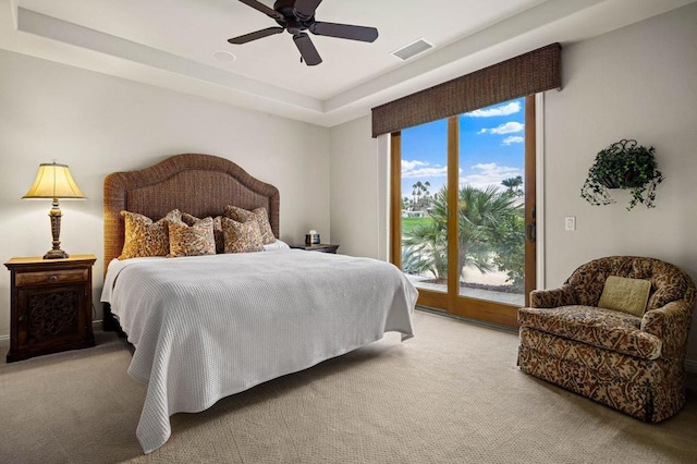 carpeted bedroom with a tray ceiling, access to outside, and ceiling fan