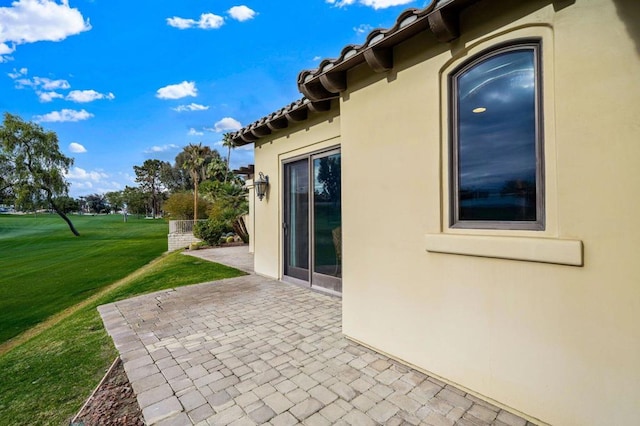 view of side of property featuring a lawn and a patio