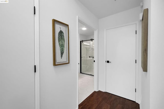 corridor with dark wood-type flooring and a barn door