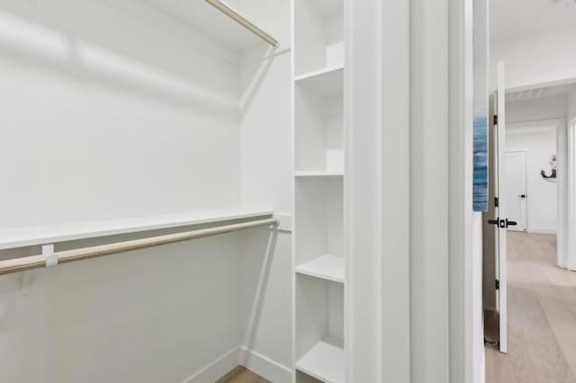 walk in closet with light hardwood / wood-style floors