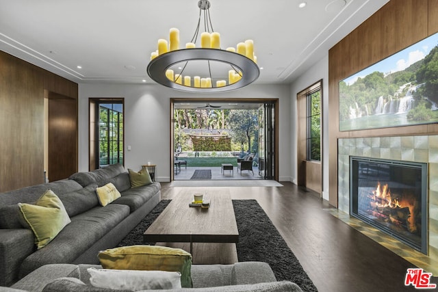 living room with a tiled fireplace, hardwood / wood-style flooring, a healthy amount of sunlight, and an inviting chandelier