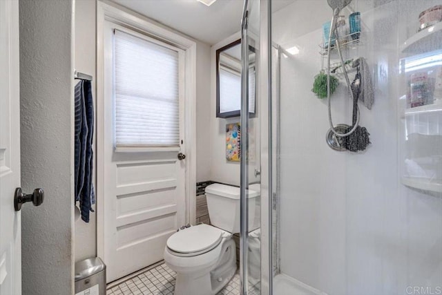 bathroom with tile patterned floors, toilet, and walk in shower