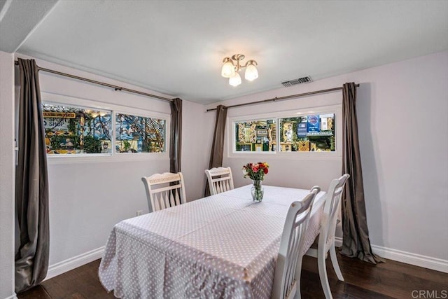 dining space with a notable chandelier, dark wood-type flooring, and a healthy amount of sunlight