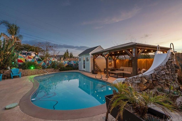 pool at dusk featuring a water slide, outdoor lounge area, and a patio area