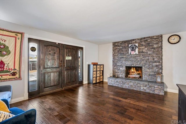 unfurnished living room featuring a stone fireplace and dark hardwood / wood-style floors