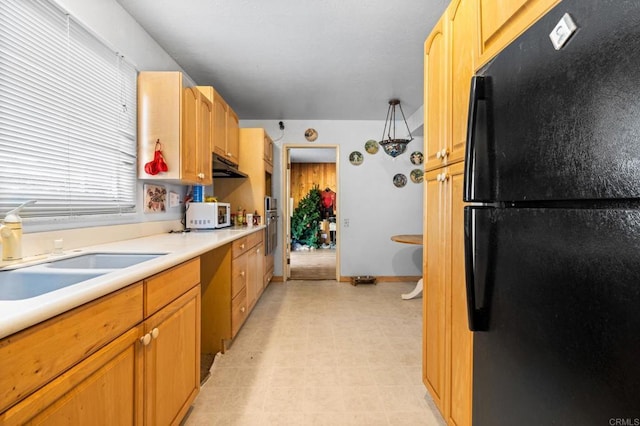 kitchen featuring stainless steel oven, black refrigerator, sink, and light brown cabinetry