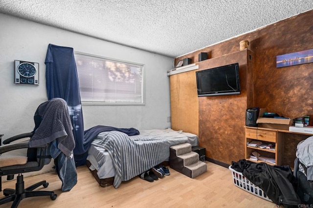 bedroom with a textured ceiling and light wood-type flooring