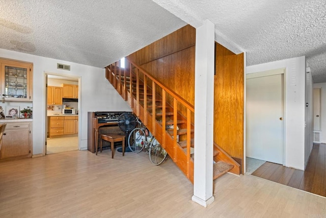 stairs featuring wood-type flooring and a textured ceiling