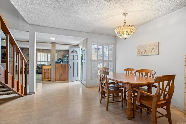 dining area with light hardwood / wood-style floors and a textured ceiling