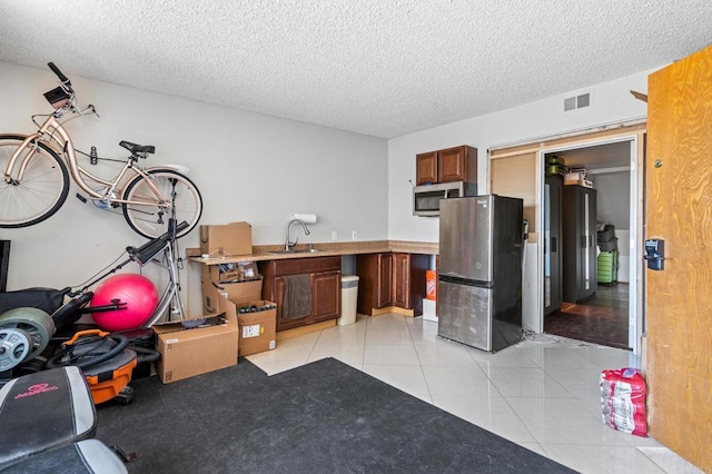 kitchen featuring appliances with stainless steel finishes, sink, a textured ceiling, and light tile patterned floors