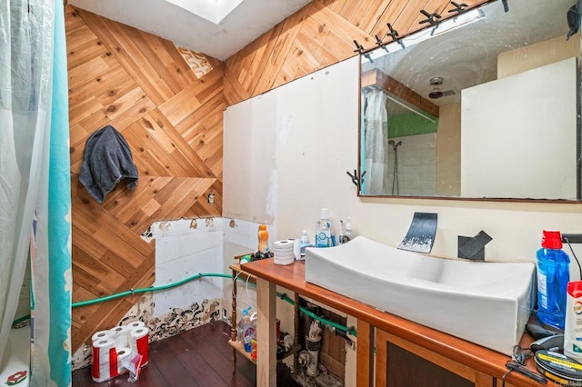 bathroom featuring wood-type flooring, sink, wood walls, and a skylight