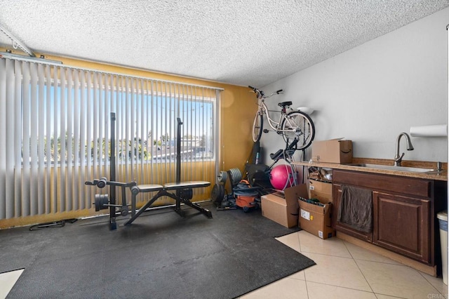 exercise room with sink, a textured ceiling, and light tile patterned floors