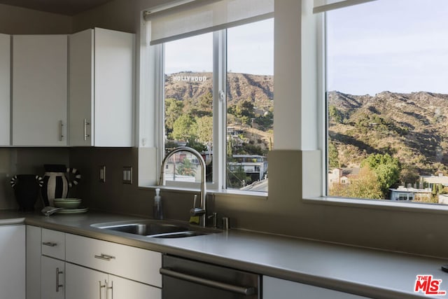 kitchen featuring white cabinetry, a mountain view, sink, and stainless steel dishwasher