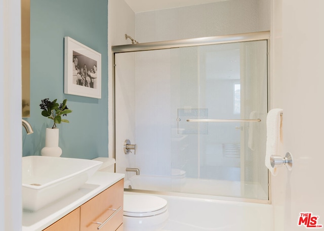 full bathroom featuring vanity, enclosed tub / shower combo, and toilet