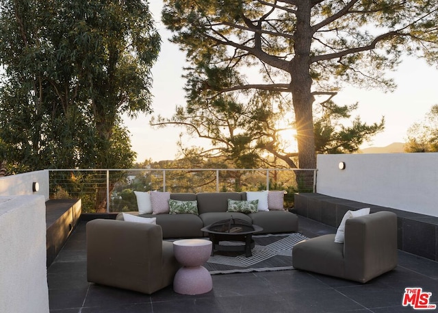 patio terrace at dusk featuring an outdoor living space with a fire pit