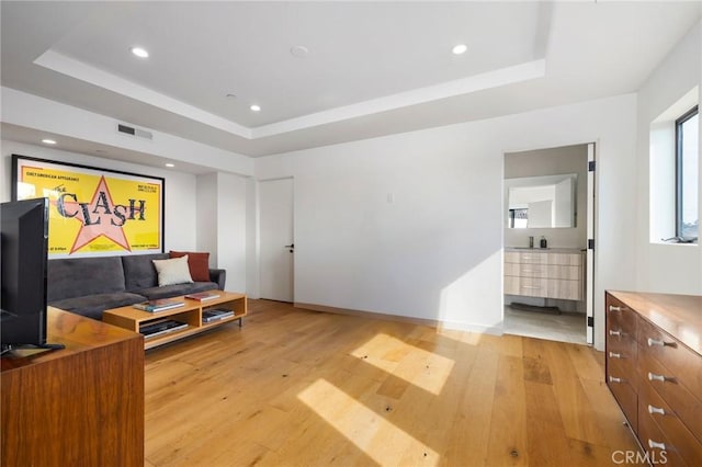 sitting room featuring light hardwood / wood-style flooring and a raised ceiling