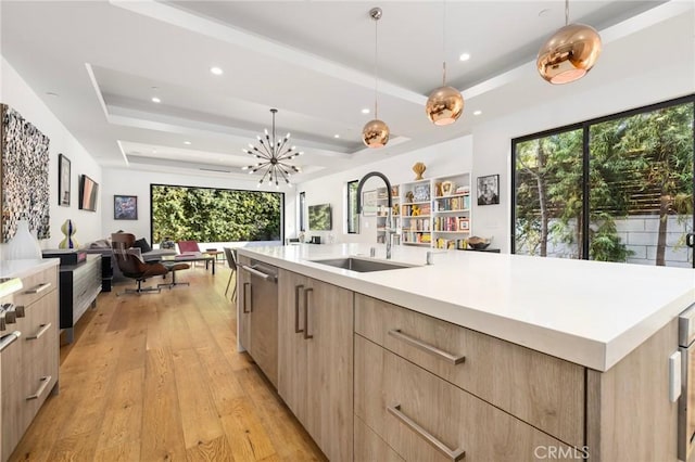 kitchen with a spacious island, a tray ceiling, sink, and pendant lighting