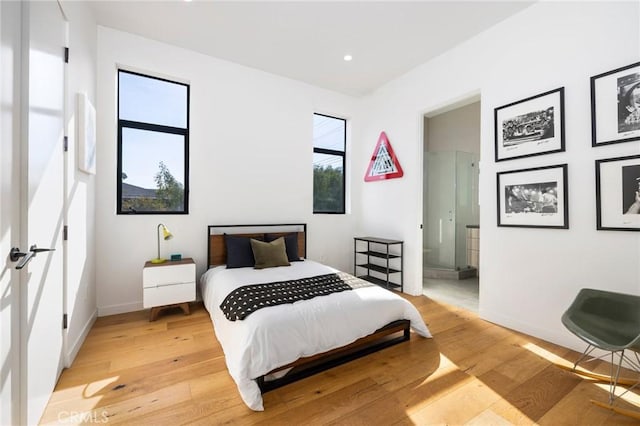 bedroom with ensuite bathroom and light hardwood / wood-style floors