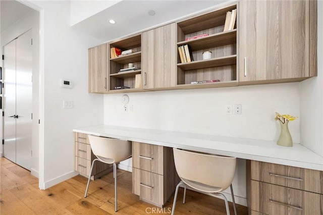 office featuring built in desk and light hardwood / wood-style floors