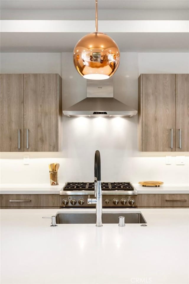 kitchen with sink, hanging light fixtures, and wall chimney range hood