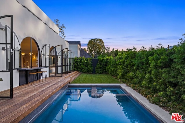 pool at dusk with a deck and a bar