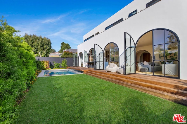 rear view of house featuring a yard, a patio, and a swimming pool side deck