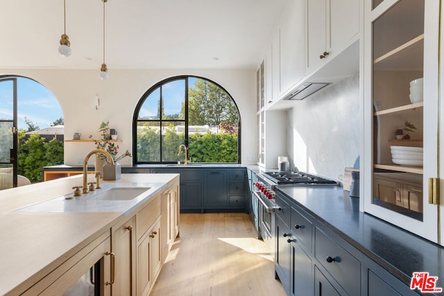 kitchen featuring sink, light hardwood / wood-style flooring, gray cabinets, high end stainless steel range oven, and decorative light fixtures