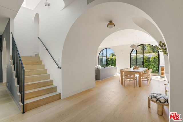 interior space featuring a towering ceiling and light hardwood / wood-style flooring