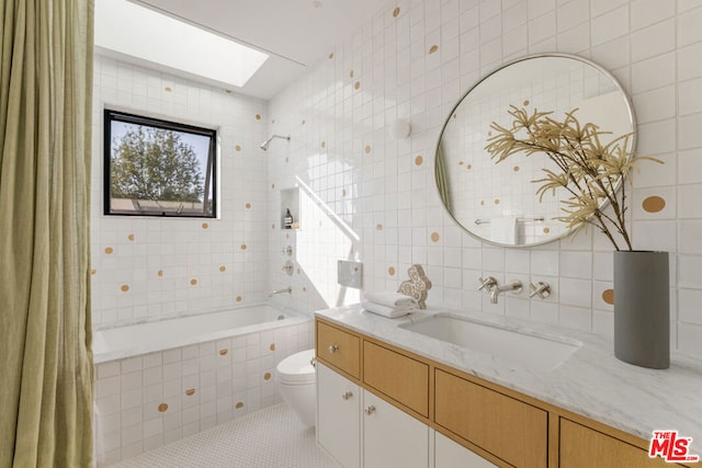 full bathroom featuring tiled shower / bath, a skylight, tile walls, vanity, and toilet