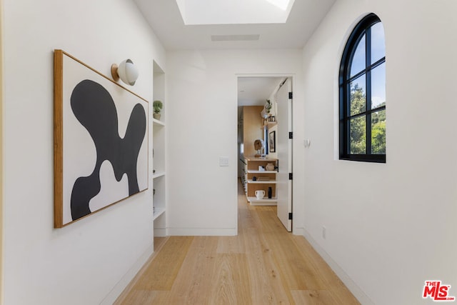 hallway with a skylight and light hardwood / wood-style flooring