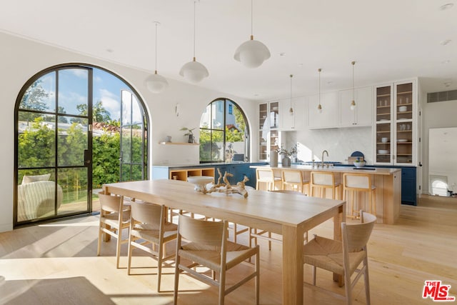 dining room featuring a healthy amount of sunlight, sink, and light hardwood / wood-style flooring