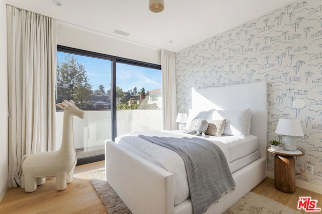 bedroom with access to exterior and light hardwood / wood-style flooring