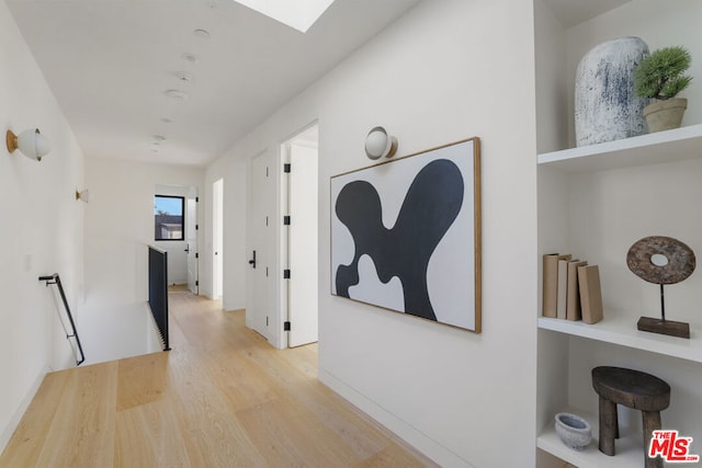 corridor featuring light hardwood / wood-style floors and a skylight