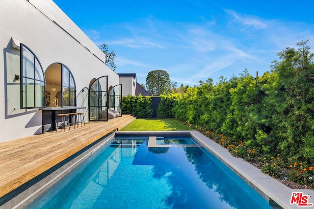 view of swimming pool featuring a deck and exterior bar