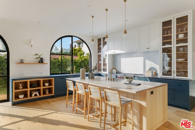 kitchen with pendant lighting, a breakfast bar, light hardwood / wood-style floors, blue cabinets, and decorative backsplash