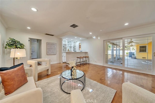 living room featuring crown molding, light hardwood / wood-style floors, and ceiling fan