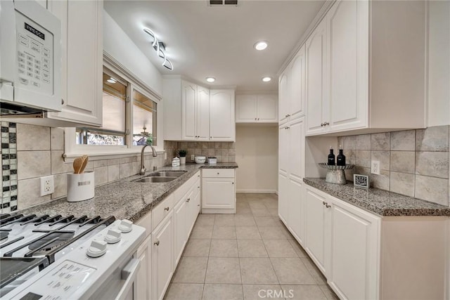 kitchen with sink, gas stove, and white cabinets