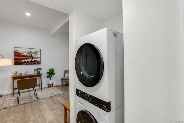 laundry area with stacked washing maching and dryer and light hardwood / wood-style flooring