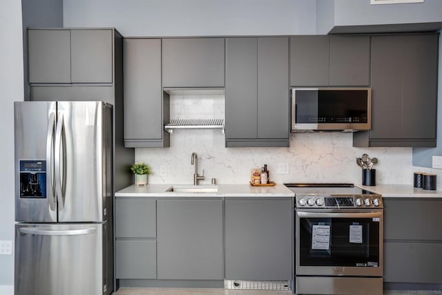 kitchen featuring tasteful backsplash, appliances with stainless steel finishes, sink, and gray cabinetry